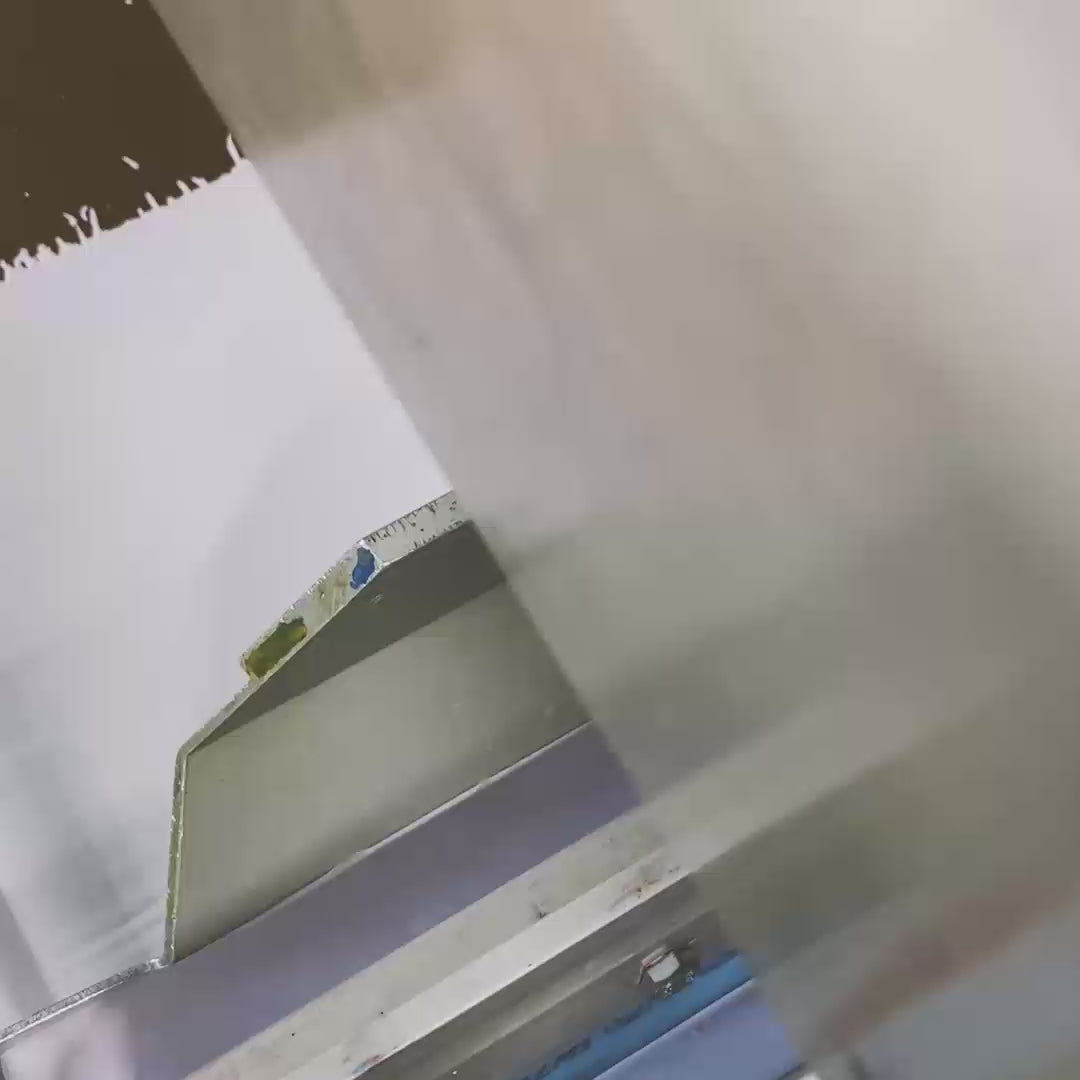 Video of a screen printing squeegee that prints a Défier lettering on an oversize T-shirt.